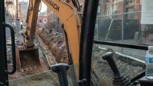 XEMACH crawler excavator trenching from cab view, documentary-style image